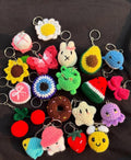 Authentic Kashmiri handmade crochet keychain collection featuring cute characters animals and fruits including frog bunny strawberry avocado donut sunflower on black background Pakistan