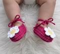 Authentic Kashmiri handmade crochet pink baby booties with white daisy flower and bow tie on newborn baby feet white fur background Pakistan