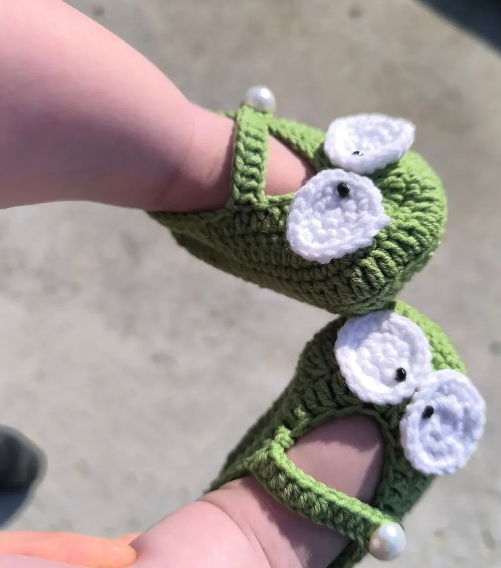 Authentic Kashmiri handmade crochet white baby sandals with daisy flower and ankle tie on infant baby feet white background Pakistan