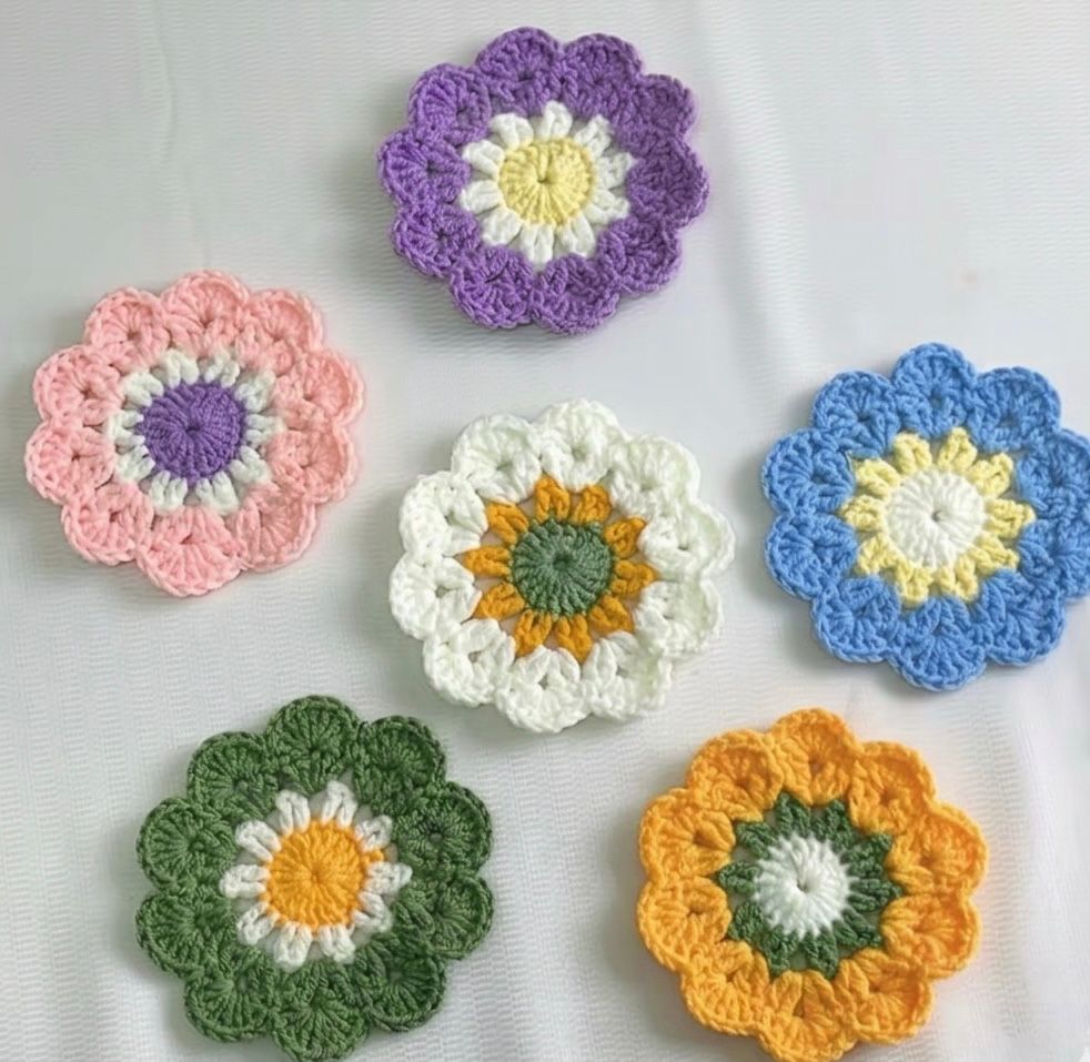 A set of six colorful Kashmiri handmade crochet flower coasters in purple, pink, white, blue, green, and orange.